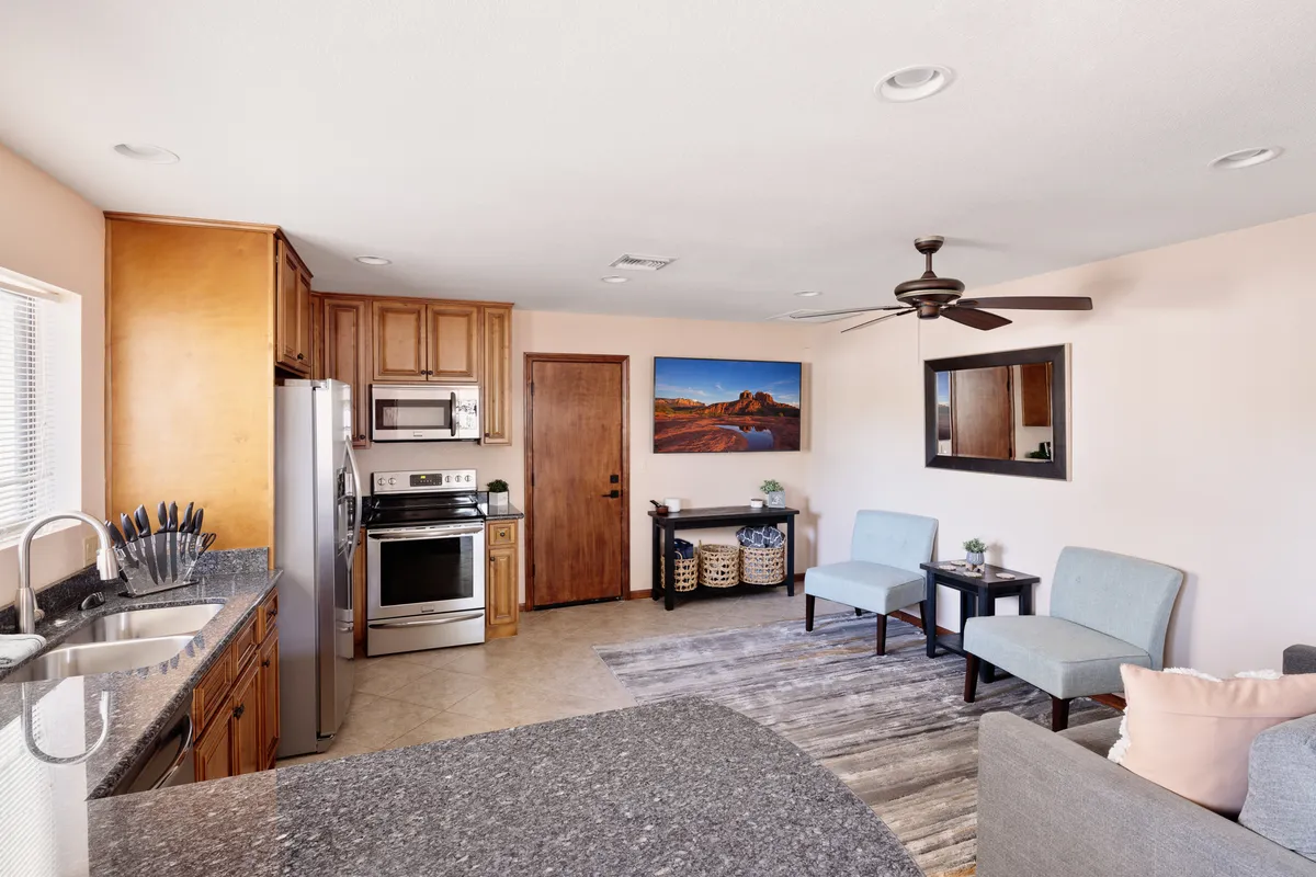 A welcoming kitchen and living area with a granite-topped island, modern stainless steel appliances, and light blue chairs. The space is designed for gatherings, with comfortable seating for entertaining, and decorative touches that create a homey yet upscale vibe.