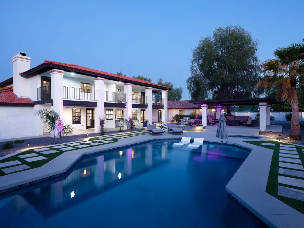 The hero image showcases a stunning Scottsdale estate bathed in golden light, with a sparkling swimming pool as the centerpiece. Elegant outdoor seating areas invite relaxation, surrounded by lush palm trees and stylish architectural details of the house. The scene evokes tranquil luxury, perfect for both serene afternoons and lively evening gatherings.