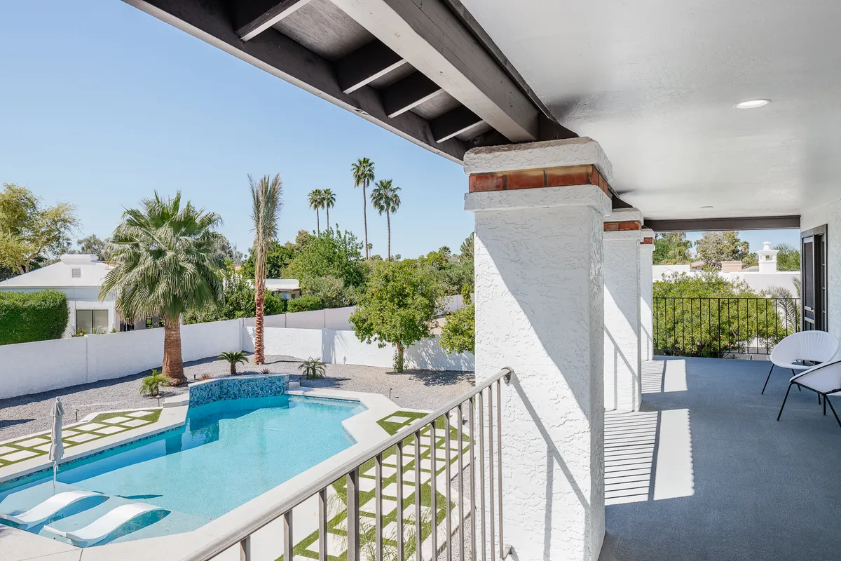 A tranquil exterior setting featuring a swimming pool bordered by palm trees, a landscaped garden, and a balcony overlooking the area. The scene invites sunbathing, swimming, or enjoying the tranquil views from the balcony, with options for both relaxation and active enjoyment.